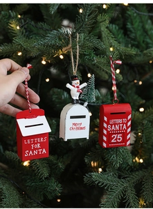 Detail of red Santa mailbox ornament with snowman hanging on a Christmas tree branch