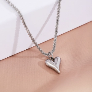 Polished heart pendant necklace with intricate popcorn chain on luxury silk background