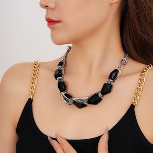 Detail of necklace with black faceted beads and woven silver metal chain on model