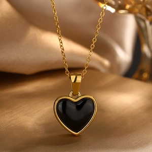 Elegant gold chain necklace with a black heart pendant on a luxury silk background