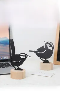 Detail of bird silhouette iron card holder with a wooden base for table decoration