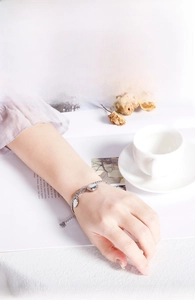 Detail of silver stainless steel chain bracelet with heart and round charms on wrist