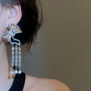 Close-up of bow tassel earrings with zircon and pearls worn by a female model