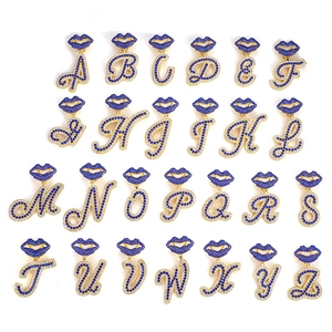 Set of 26 gold iced out letter pendants featuring blue lip designs with sparkling crystals