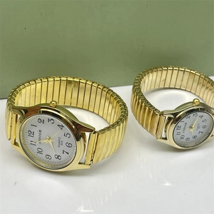 Macro shot of gold elastic strap watches with white dials and large numbers for couples