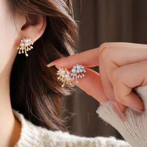 Detail of fireworks-style gold pearl earrings worn and held to show texture and design