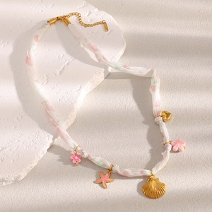 Detail of 18K gold plated ribbon necklace with seashell, starfish, and heart charms