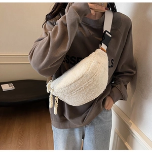 Close-up of white plush crossbody bag with beige strap and black buckle on a model