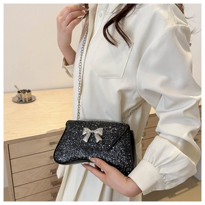 Close-up of black sequined evening bag with a silver bow and elegant chain strap