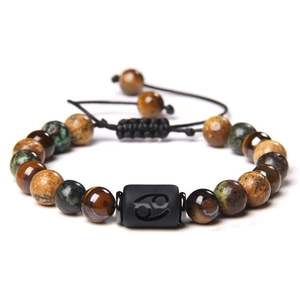 Detailed shot of Tiger Eye bead bracelet with Cancer zodiac sign on a black rectangular bead