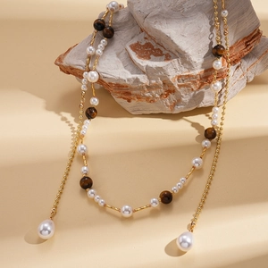 Elegant vintage long necklace with pearls and brown tiger eye stones on stone prop