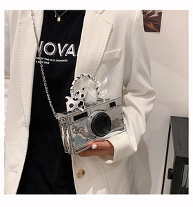Detail of silver camera-shaped crossbody bag with polka dot ribbon and chain strap