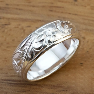 Classic silver Hawaiian flower vine engraved wide band ring on a natural wood surface