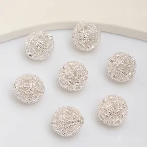 Detalle macro de cuentas caladas plateadas para la creación de joyas y collares hechos a mano