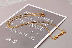 Detailed view of three golden fish pendants on a minimalist stainless steel O-chain