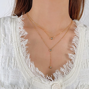 Detail of layered gold stainless steel necklace with sparkling round zircon pendants on model
