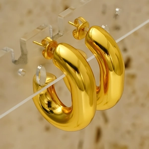 Chic hollow C-shaped hoop earrings in polished gold titanium steel on a display stand