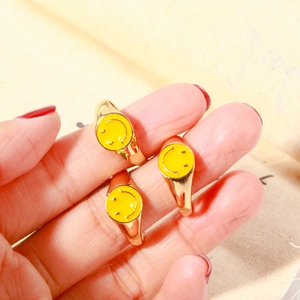 Set di 3 anelli dorati con smile in smalto giallo indossati elegantemente sulla mano