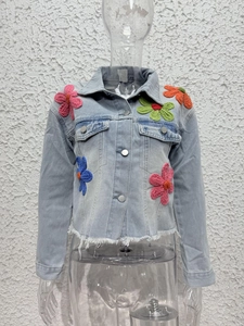 Detailed macro view of colorful crochet floral patches on light blue washed denim jacket
