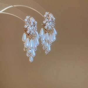 Detail of luxury pearl tassel earrings with marquise rhinestones on gold metal base