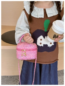 Close-up of pink tweed girl's crossbody bag with gold chain and spherical zipper detail