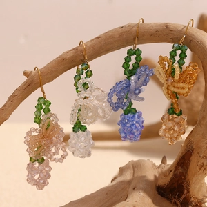 Handmade beaded grape earrings in pink, blue, white, and amber on a rustic wood branch