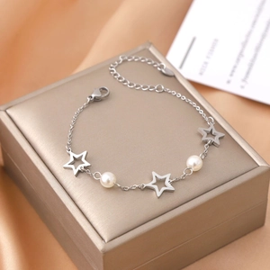 Star and pearl stainless steel bracelet with cutout charms on a jewelry box