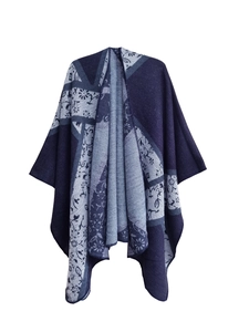 Detail view of the intricate floral and geometric jacquard knit pattern on a blue poncho