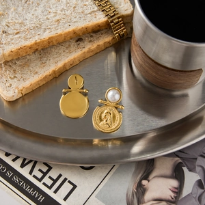 Vintage gold coin earrings with pearl detail and Victorian embossing on a metal tray