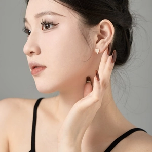 Close-up of model wearing heart-shaped stud earrings with sparkling pave-set zircons
