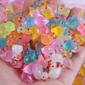 Bulk luminous resin mini ducks in assorted colors held in hand for DIY decor
