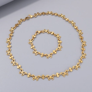 Detail of gold butterfly link necklace and bracelet set on light gray background