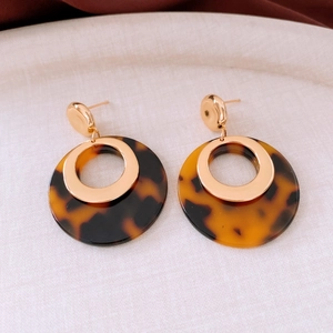 Detail view of 18K gold plated resin hoop earrings featuring a tortoiseshell pattern