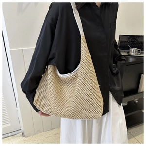 Detail of woven straw shoulder bag featuring white straps and trim on a beige texture
