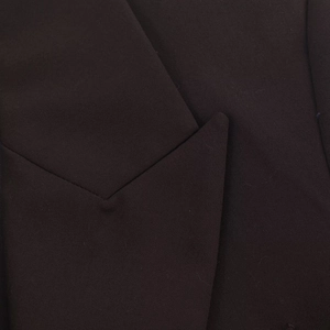 Gros plan du revers d'un blazer sombre montrant la texture du tissu en sergé de qualité