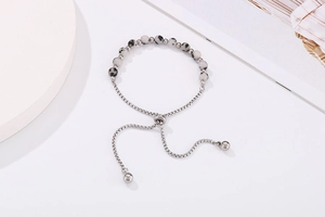 Detail of adjustable gold slider bracelet with spotted stone beads and box chain link