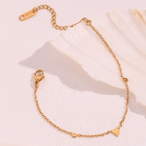 Detailed macro view of 18K gold plated heart pendant on a thin link chain bracelet