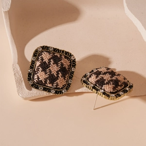 Macro detail of square houndstooth fabric stud earrings with vintage gold rhinestones