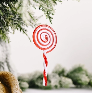 Red and white spiral acrylic candy cane ornaments hanging on a snowy Christmas tree branch