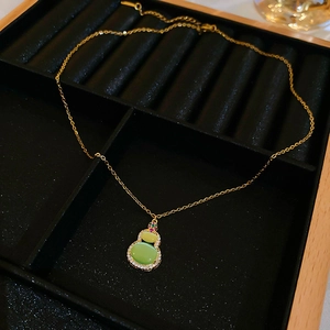 Macro detail of a gold gourd pendant necklace with green cat-eye stone and zircons