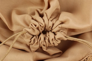 Close-up of the woven drawstring closure and natural folds on a khaki beach tote bag