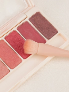 Close-up of matte and shimmer eyeshadow palette with a pink blending brush