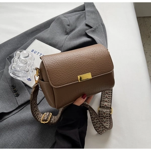 Détail du sac marron à motif litchi avec boucle dorée et large bandoulière jacquard