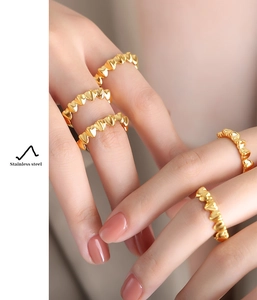 Detail shot of heart-shaped stainless steel rings stacked on model's fingers