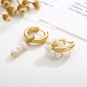 Vintage hollow titanium steel earrings with pearls and gold finish on minimalist background