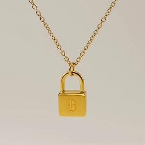 Macro view of gold padlock pendant with Gothic letter B engraving on a delicate chain
