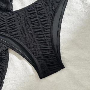 Detail of black pleated texture fabric on three-piece bikini bottoms with wavy effect