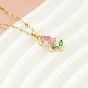 Detailed close-up of a golden tulip pendant with pink waterdrop gem and green leaf stones