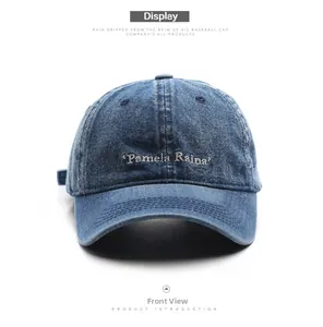 Front view of washed denim baseball cap with white Pamela Raina letter embroidery