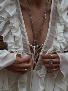 Close-up of layered silver necklaces and rings set with bohemian style details